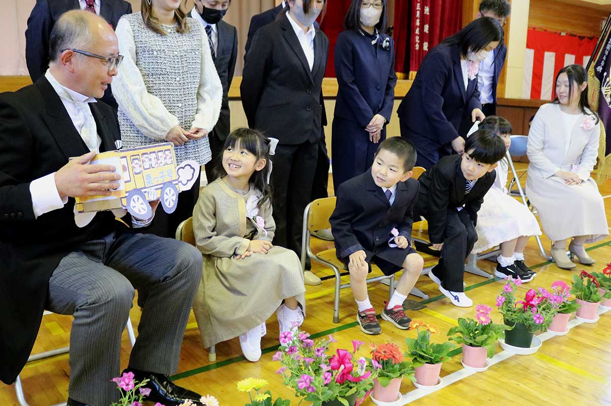 式を終え、記念撮影前のひととき。高橋校長が手にする「栗っ子号」に目がくぎ付け