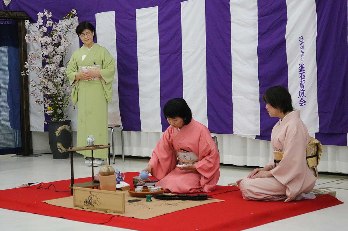 茶席には見頃のサクラにヤマブキをそえた生け花を配置。春色の着物姿の会員が煎茶道の「末広点前」を披露