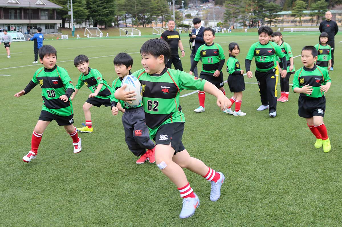 ボールを持ってグラウンドを駆け回る中学年以下の団員。タッチされたら仲間にパス