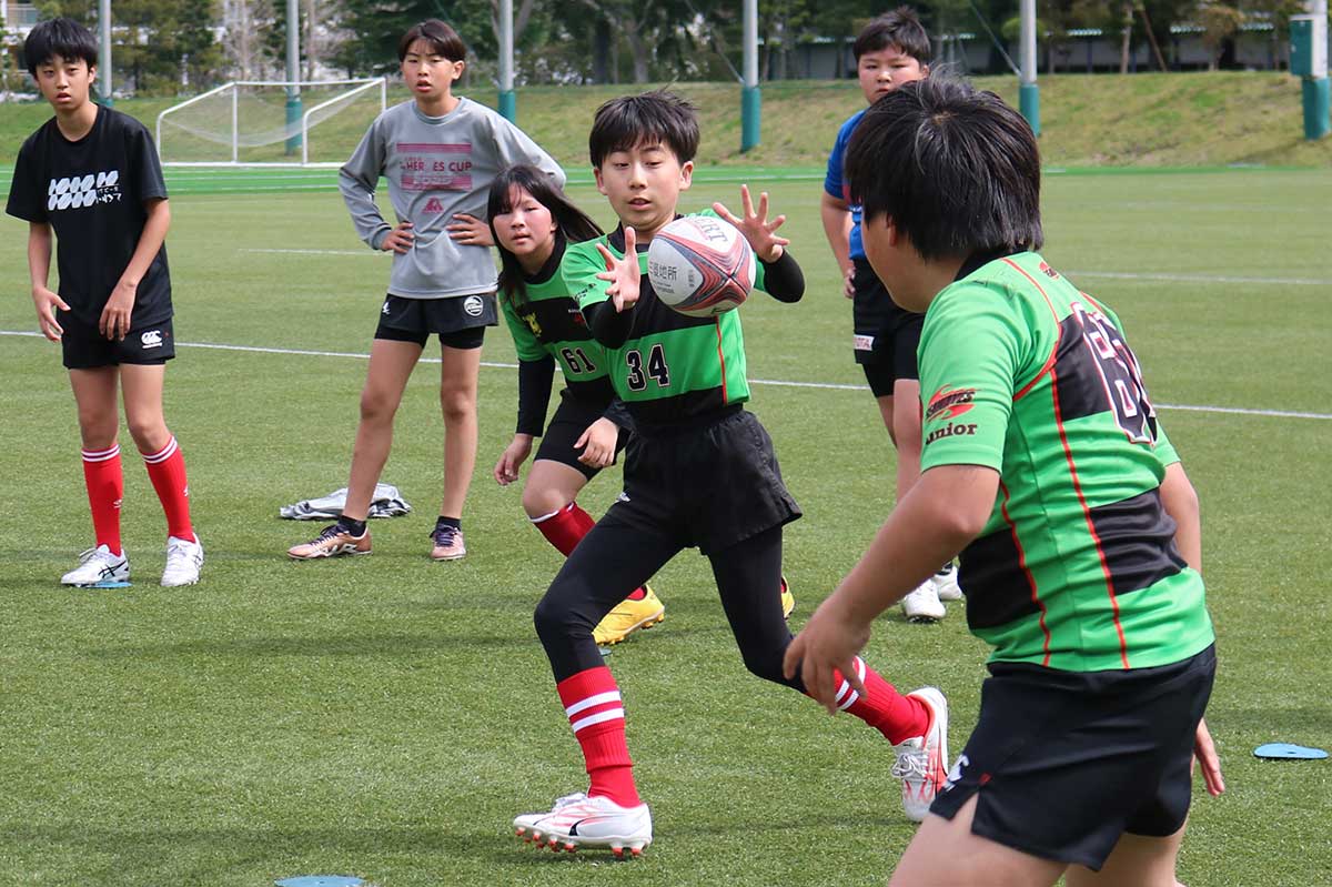 高学年のパス練習。両手指をしっかり広げてキャッチ。ジュニア卒団生（後方）も練習をサポート