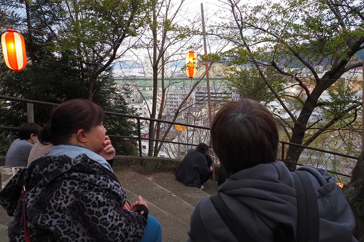 津波警報発表で、高台の薬師公園に避難した人たち。奥が釜石湾。不安そうに見つめる