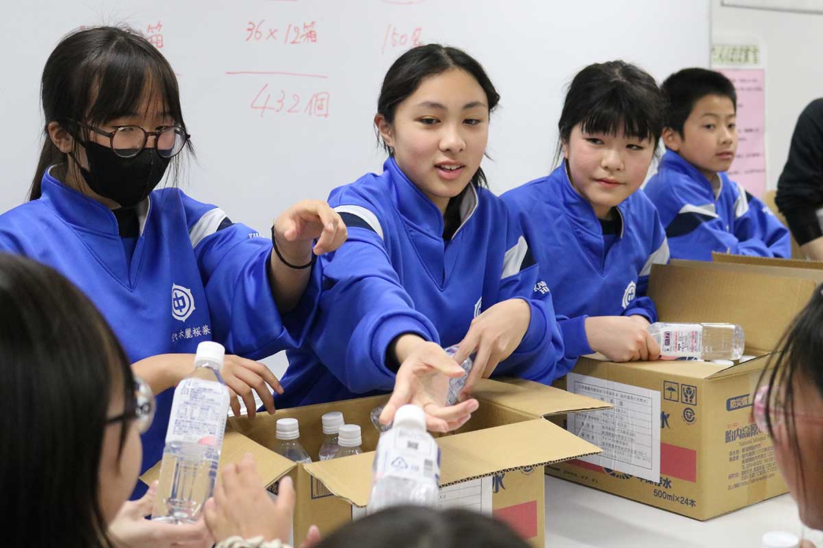 校内の備蓄倉庫から運び出した飲料水を避難者に配る釜石東中生