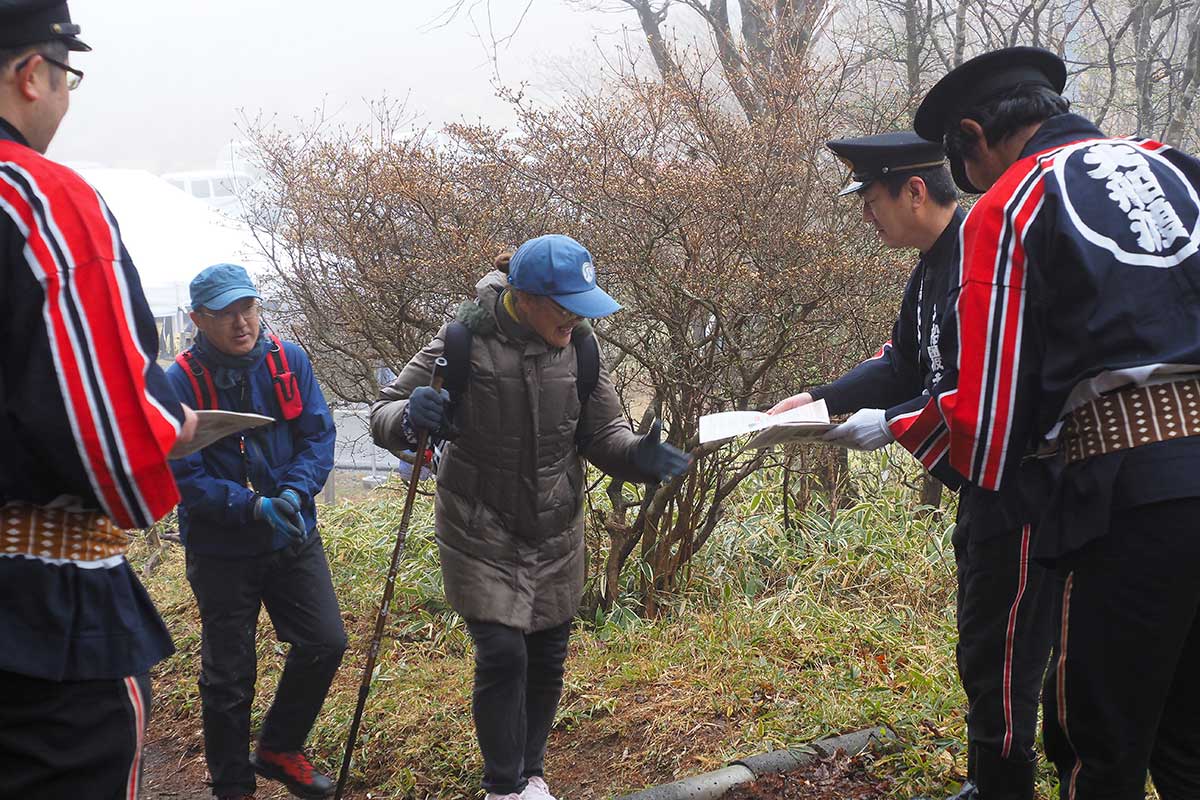 登山口で入山者にチラシを配る大船渡市消防団第9分団の団員