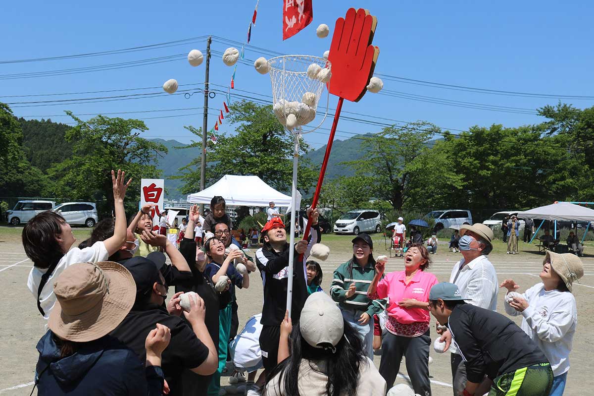地域住民参加の玉入れ。相手組の“鬼”が棒の先端の大きな手で、玉が籠に入るのをじゃまする