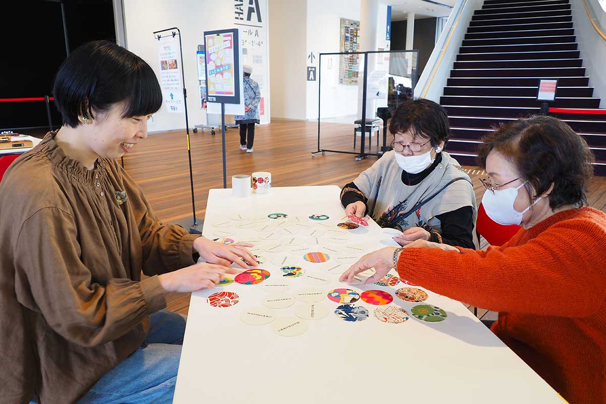 カードゲームで参加者と触れ合うTETTOスタッフ（左）