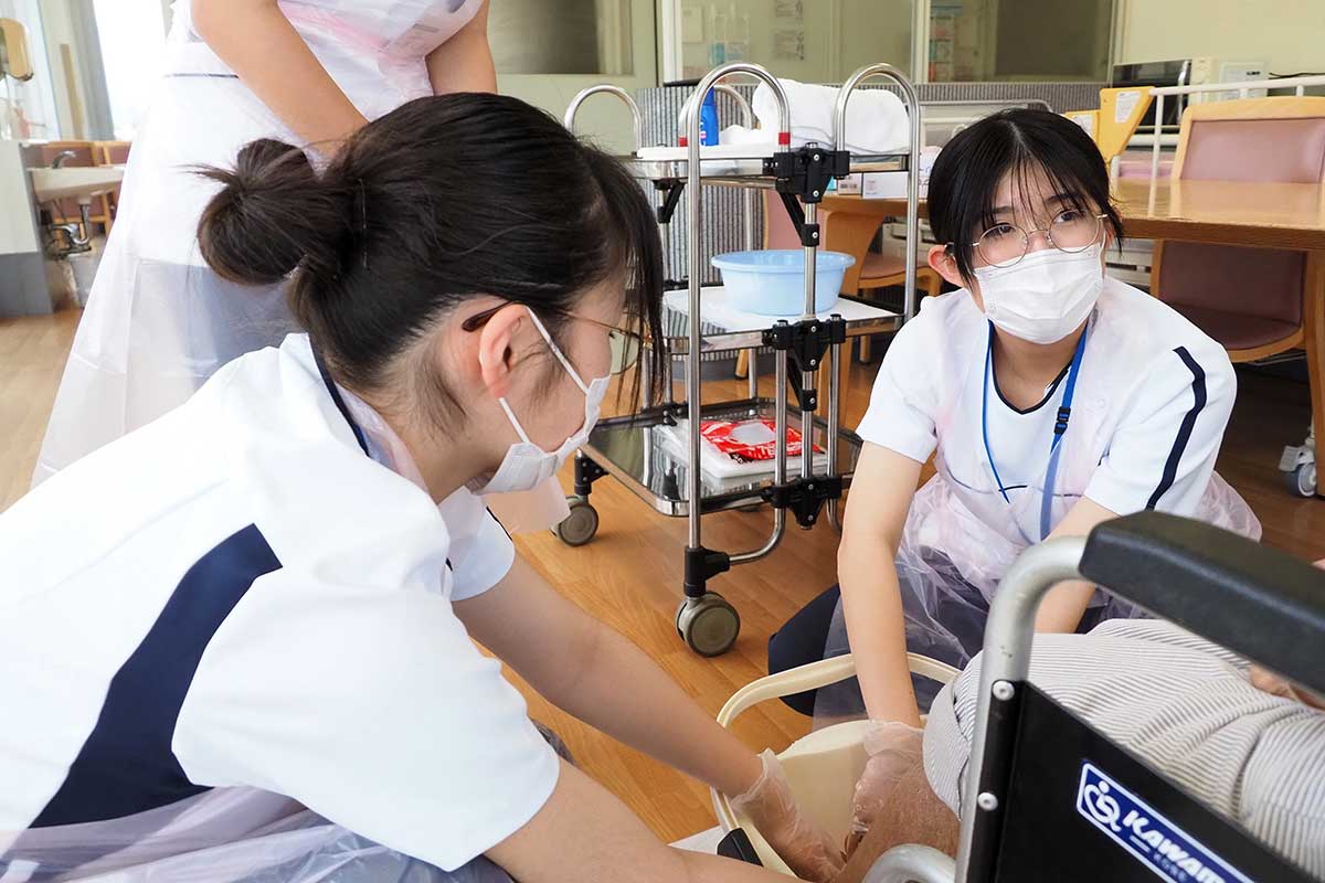 患者に声をかけながら足浴に挑戦する生徒