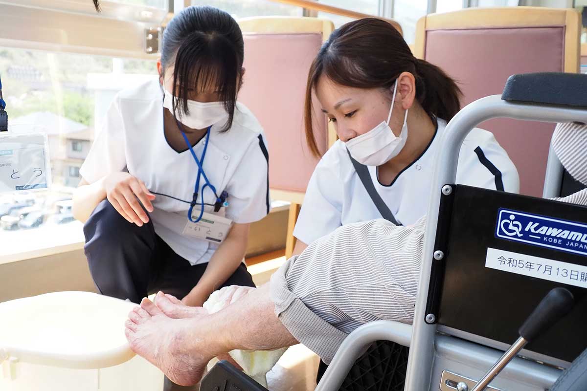 先輩看護師（右）の動きをじっと見つめ看護の心を学ぶ生徒