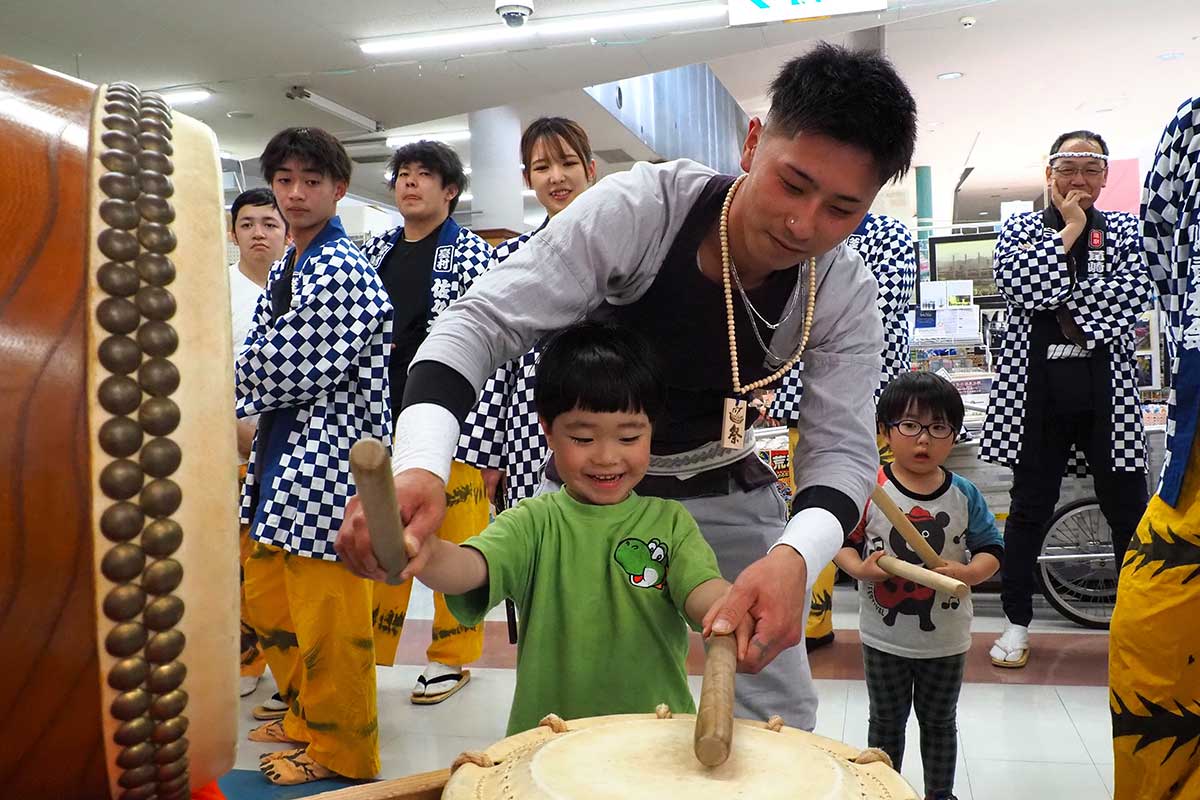 太鼓の打ち方を教わり笑顔を見せる子ども