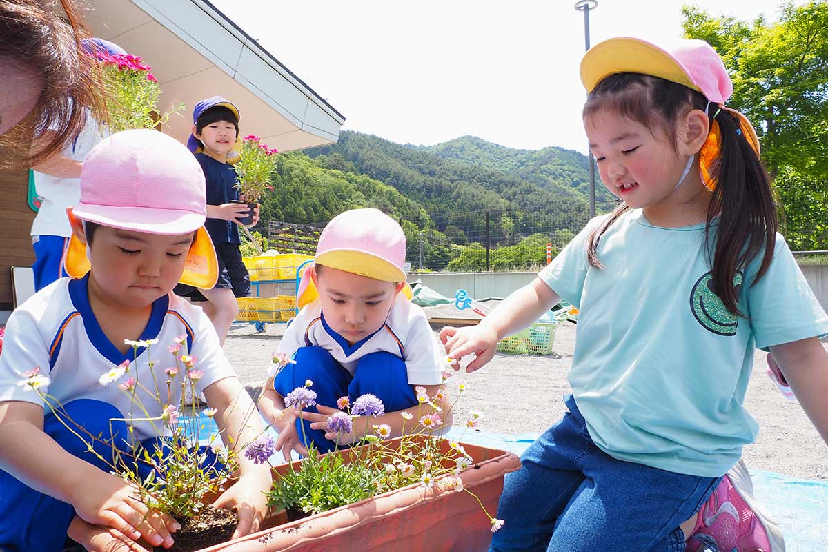 「大きくなってね」と声をかけながら花に触れる上中島こども園の園児