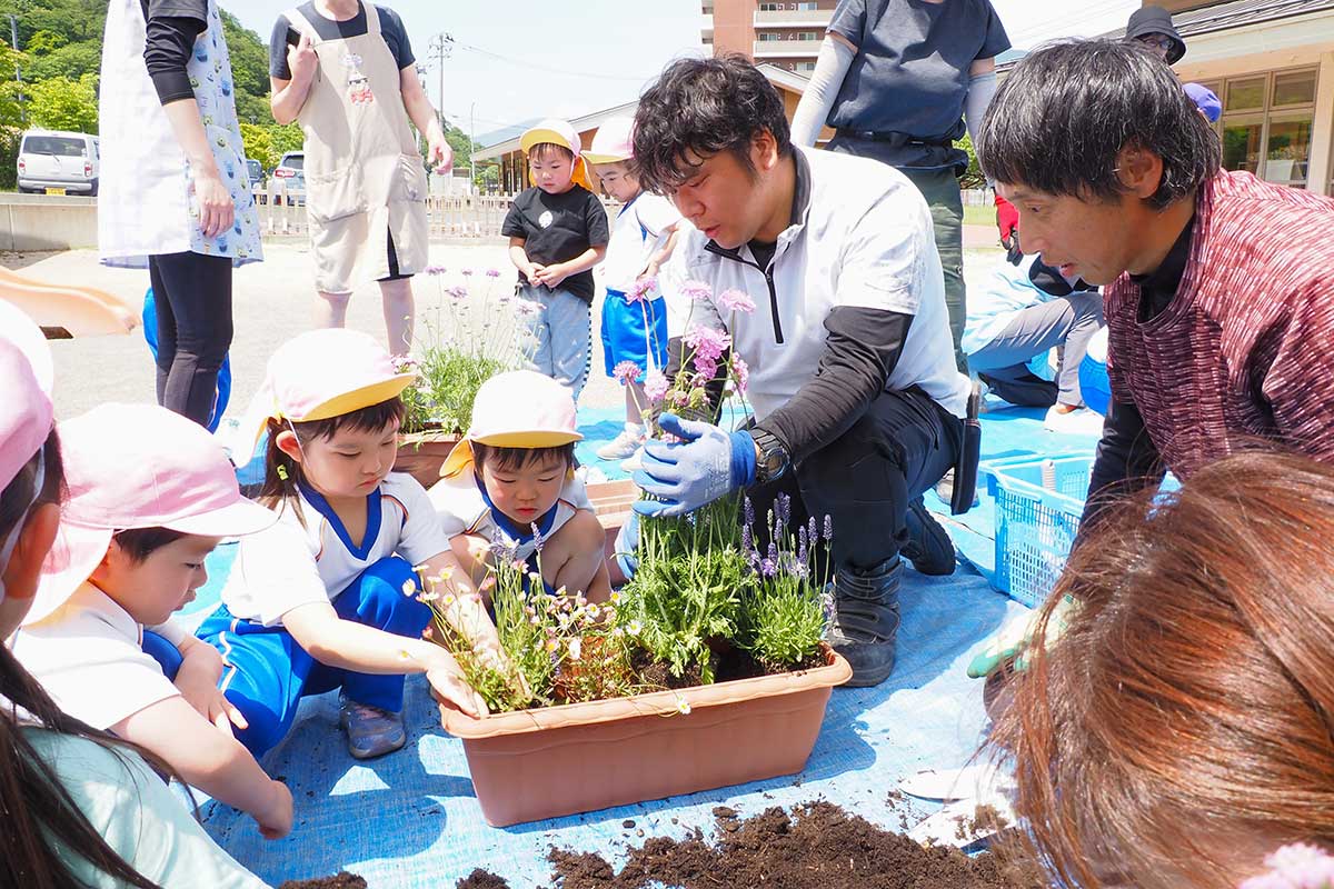 緑仁舎のスタッフに教わりながら花を植える園児たち