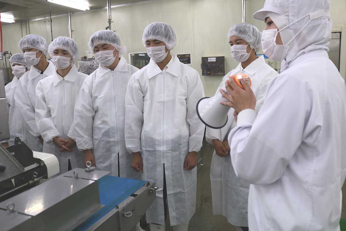 水産加工品製造の工場を見学する釜石商工高の2年生＝3日、津田商店（鵜住居町）