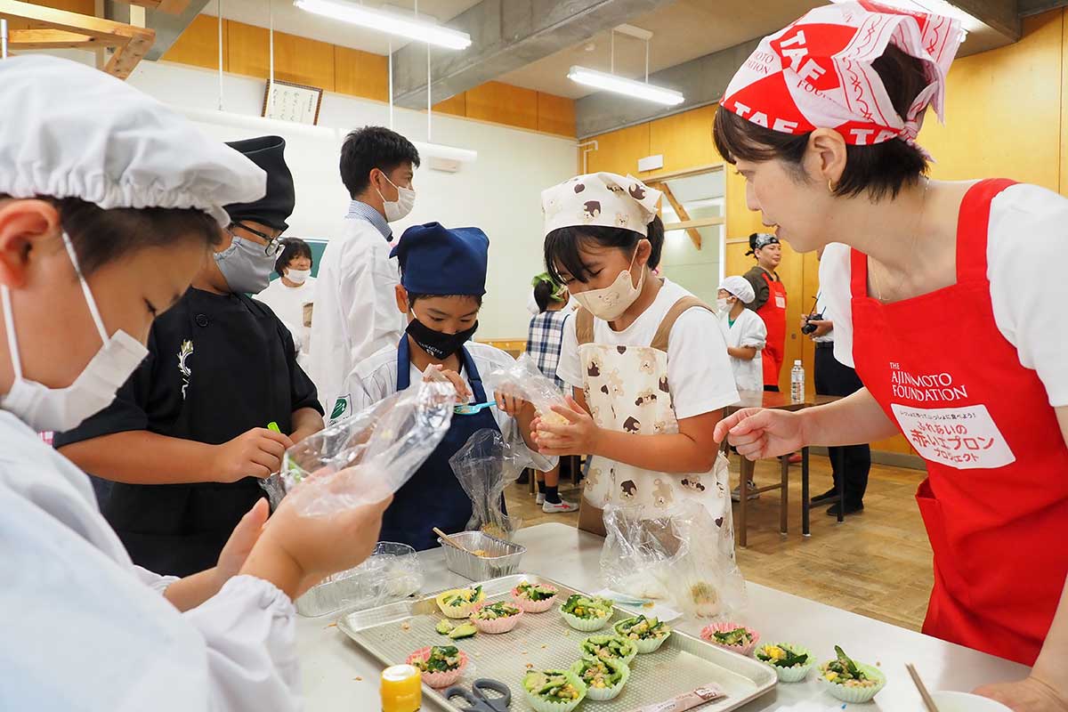 三浦優佳さん（右）から防災食の作り方を教わる白山小の児童