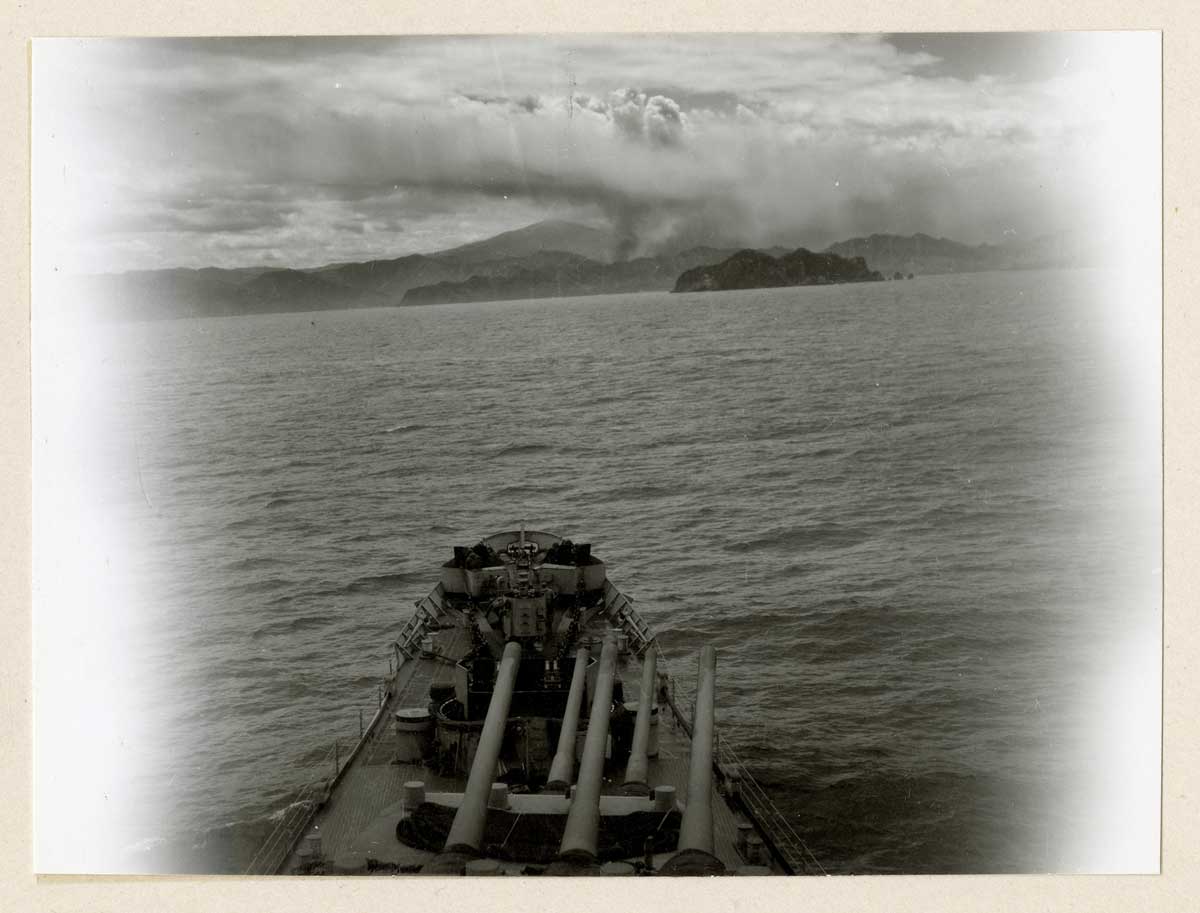 小暮聡子さんが米国立公文書館で確認した1回目の釜石艦砲射撃の写真。説明に「炎上する釜石に接近するUSSクインシー」とある=釜石市郷土資料館提供