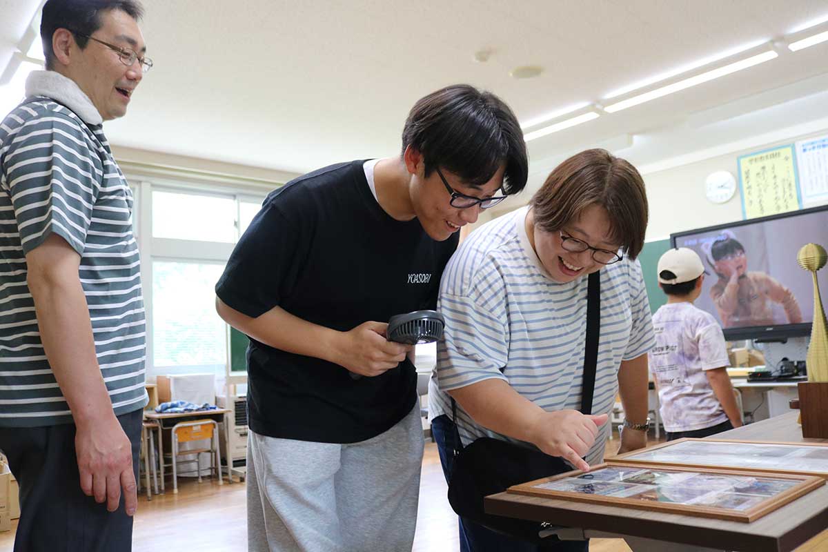 懐かしい写真を指差し、母校の様子を子どもに教える栗林小の卒業生＝15日、栗林小校舎内