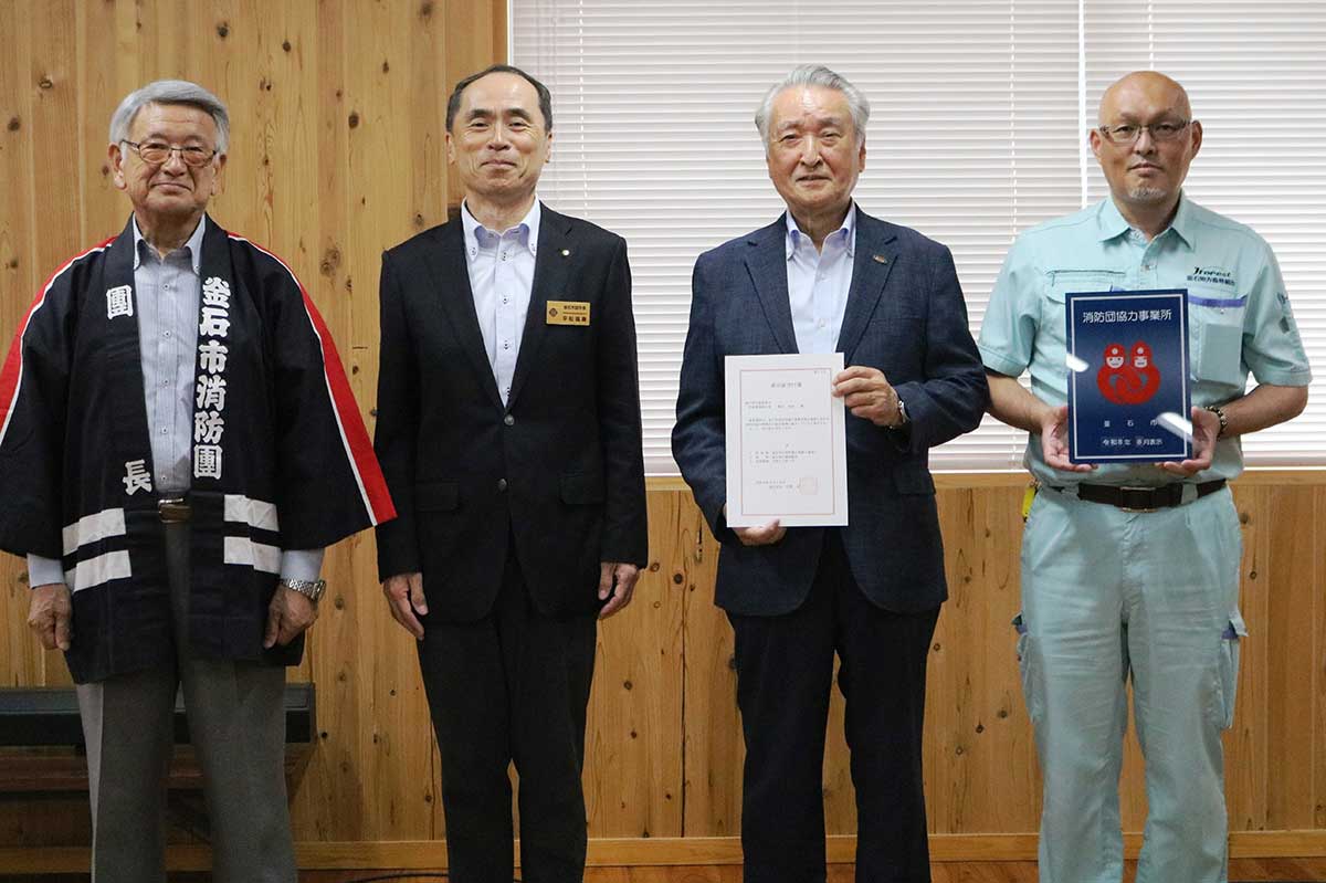 「釜石市消防団協力事業所」の交付書と表示証を手にする釜石地方森林組合の野田武則代表理事組合長(中右)と久慈雄一副参事(右)
