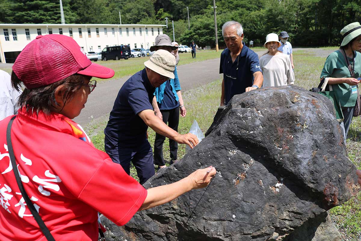 磁鉄鉱やザクロ石を含む巨大な岩石を観察。磁石を近づけてみる参加者