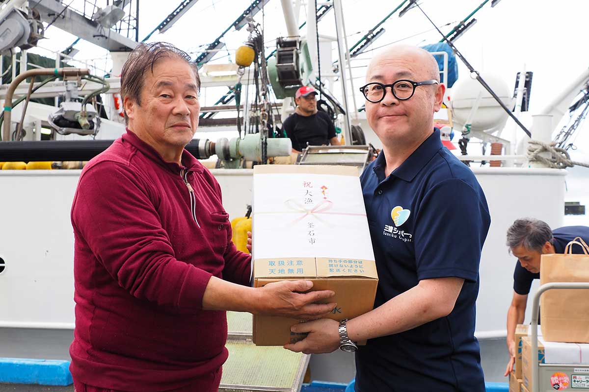 小野共市長が猟田雄輔漁労長(左)に飲料などを差し入れ