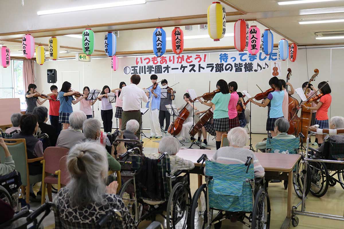 仙人の里で開かれた玉川学園オーケストラ部の慰問演奏会。ホールには歓迎のメッセージが掲げられた