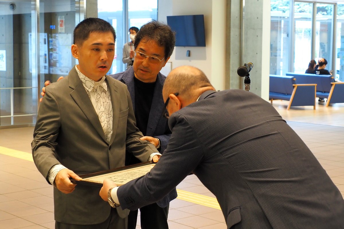 小野共市長（右）から感謝状を受け取る小林覚さん（左）、寄り添う父の俊輔さん