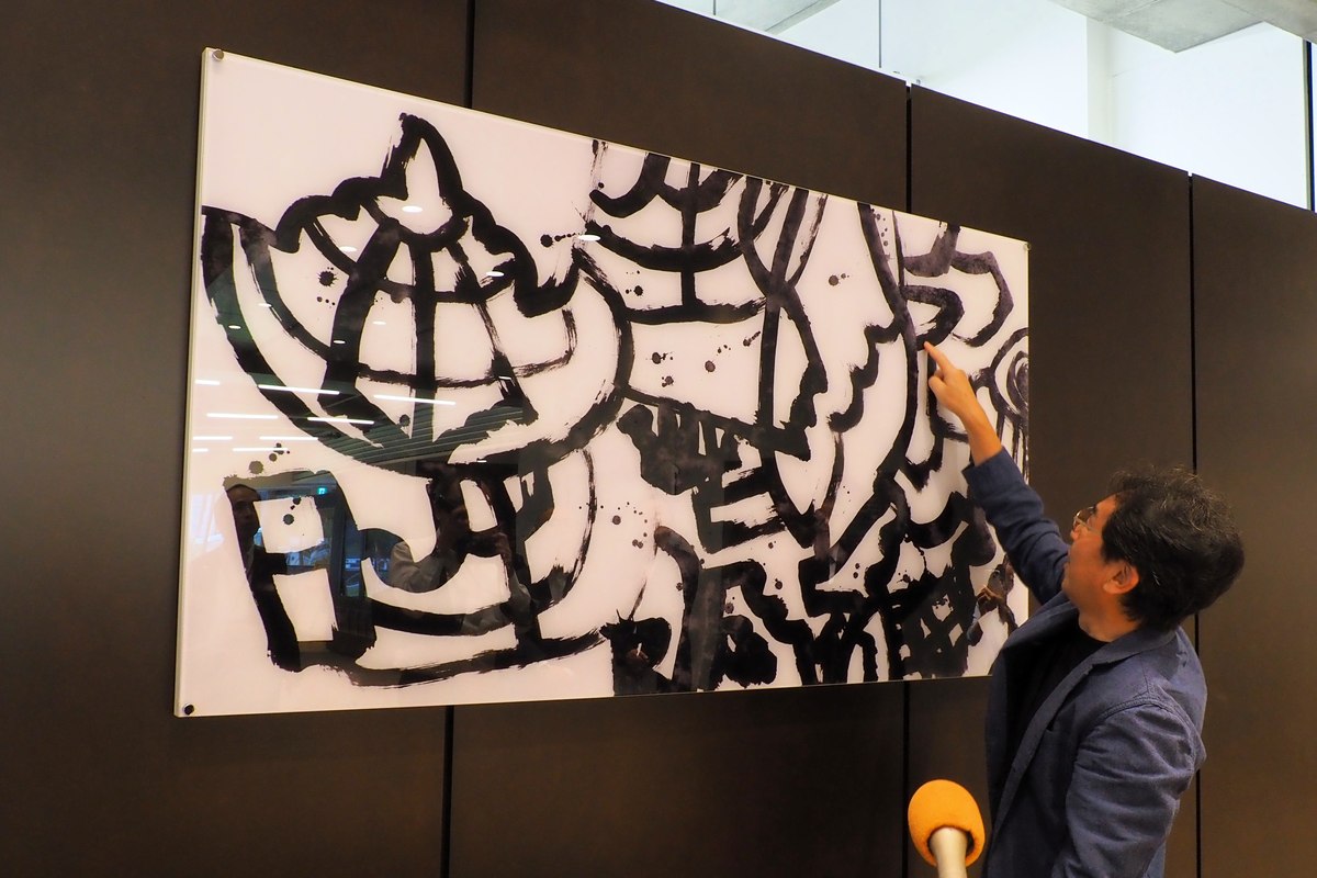 作品解説。画面の3分の2を占めるのは「鐵」という文字で、残りに「魚」「ラグビー」「かまいし（カマイシ）」が散りばめられているという。「解読を楽しんで」