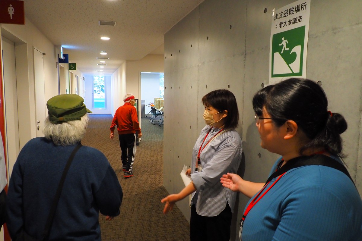 開庁後初の避難訓練で4階の大会議室に市民らを誘導する釜石市職員（右）